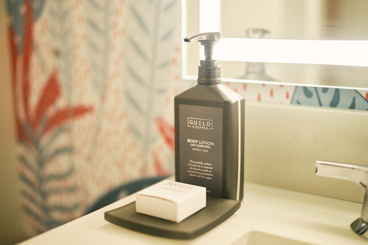 A bathroom with a white sink, a black soap dispenser, and a white soap bar on a black tray.