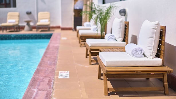A poolside area with wooden lounge chairs and a tiled pool. - Soma House (San Francisco)