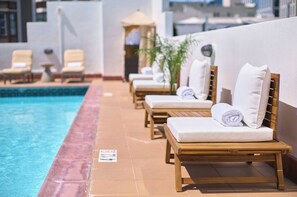A poolside area with wooden lounge chairs and a tiled pool. - Soma House (San Francisco)
