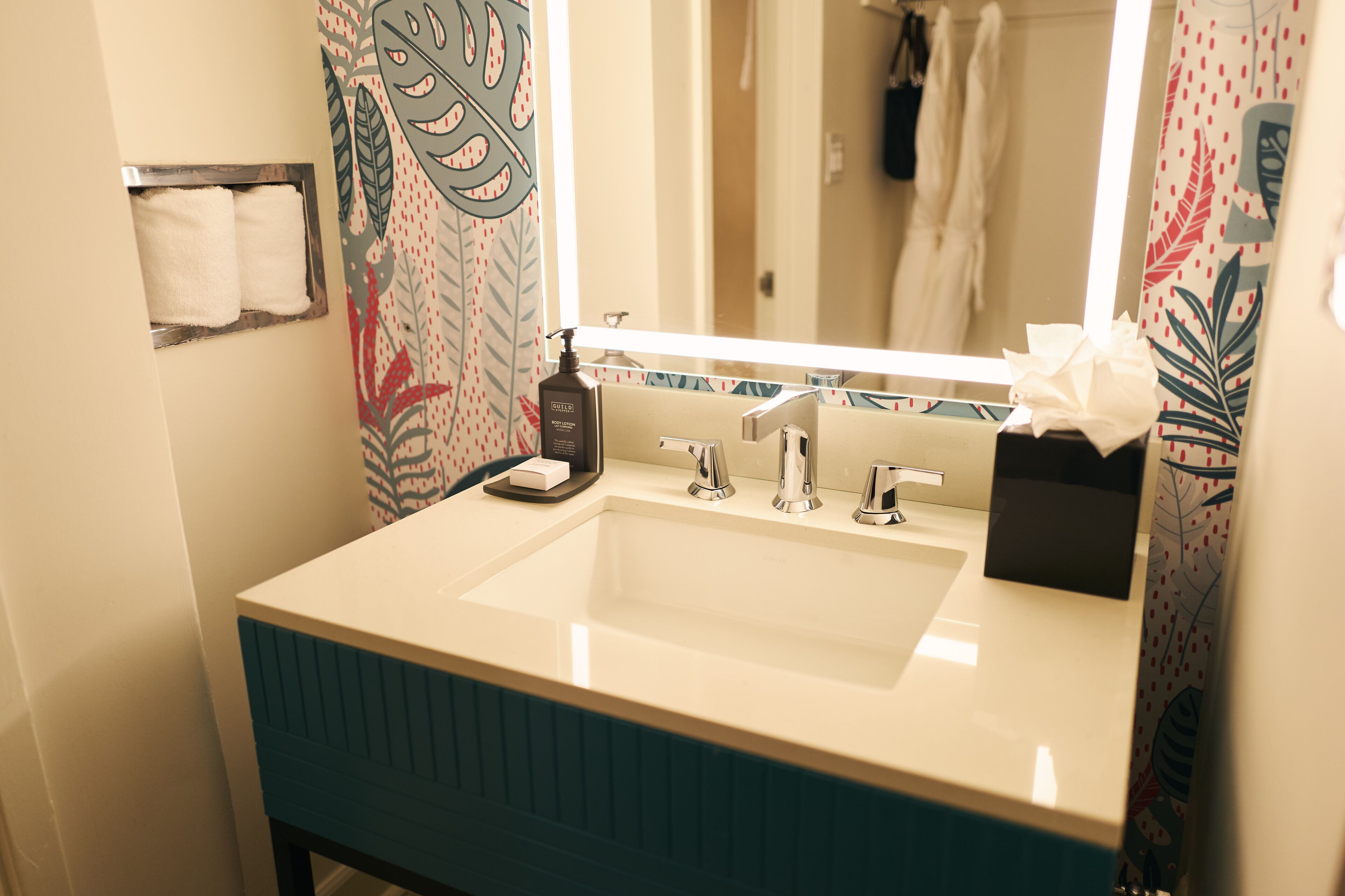 A bathroom with a white sink, a mirror, and a towel rack.