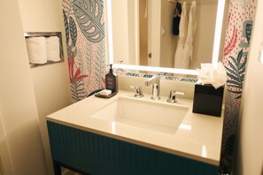 A bathroom with a white sink, a mirror, and a towel rack. - Soma House (San Francisco)