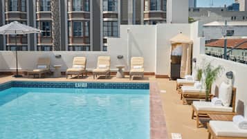 Una piscina al aire libre, sillones reclinables de piscina