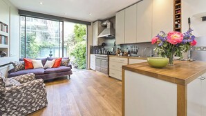 A modern kitchen with a large island, built-in cabinets, and a view of greenery outside.