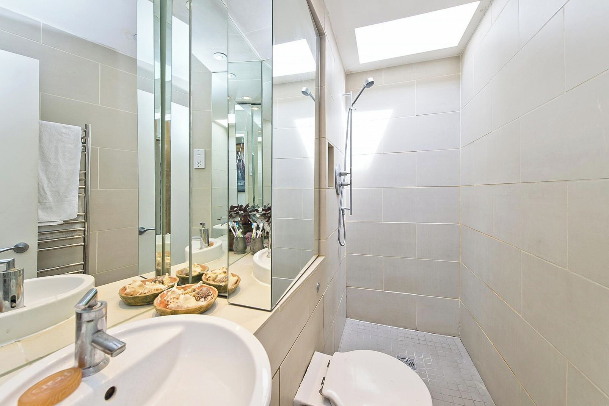 Ein modernes Badezimmer mit Duschkabine aus Glas, einem großen Spiegel und einem Waschbecken mit Seifenschale.