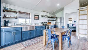 Una cocina moderna con armarios azules, electrodomésticos de acero inoxidable y una mesa de comedor de madera con sillas azules.