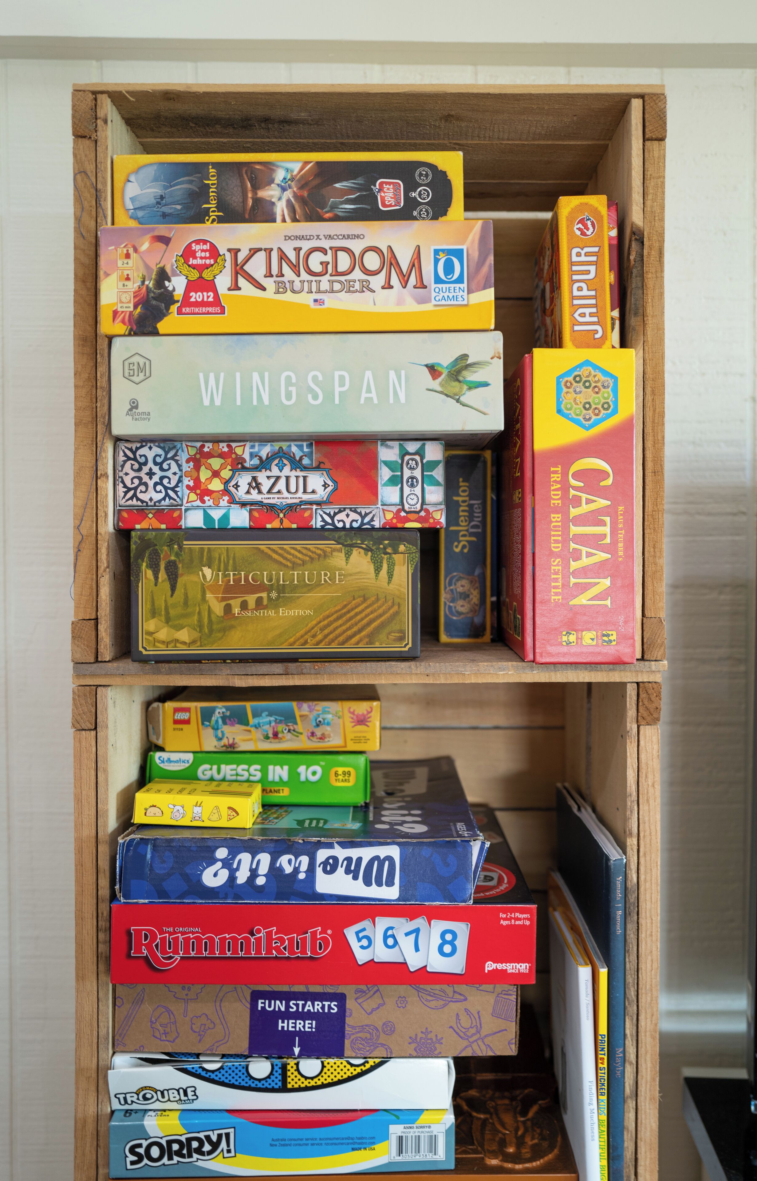 A wooden shelf with various board games stacked on it.