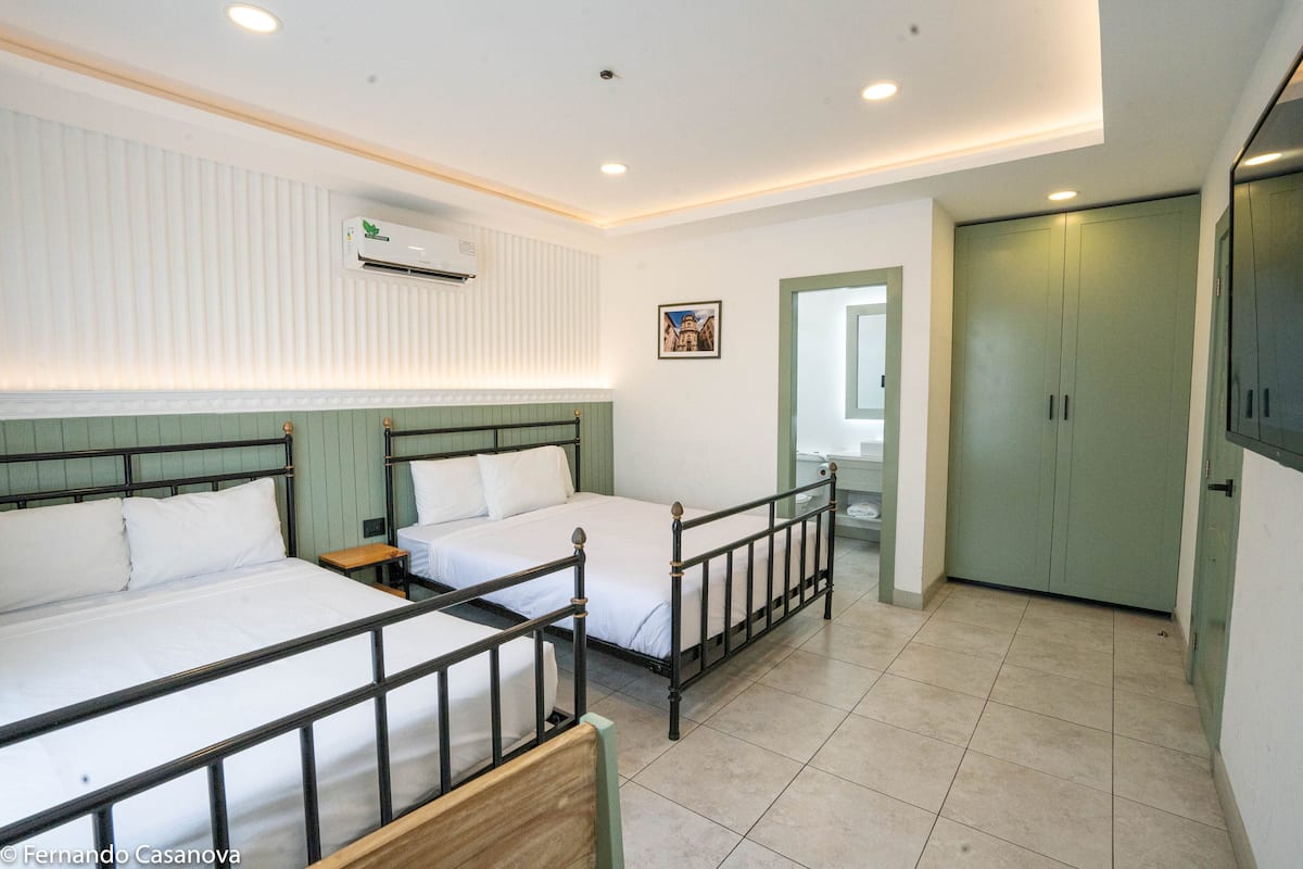 A room with two beds, a wardrobe, and an air conditioning unit.