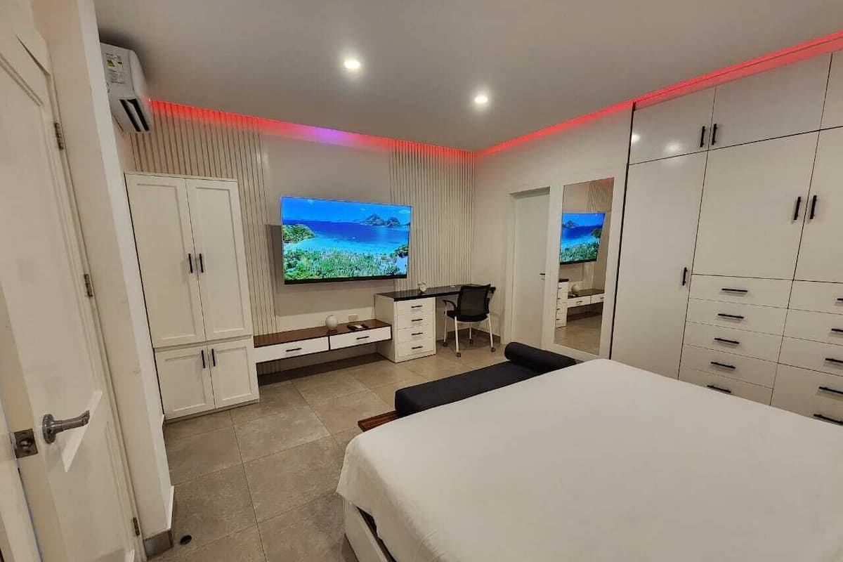 A modern bedroom with a large bed, a desk, and a TV.