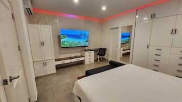 A modern bedroom with a large bed, a desk, and a TV.
