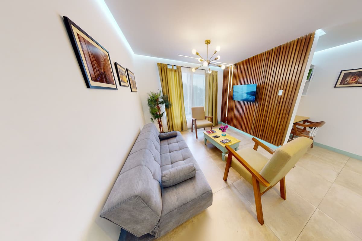 A modern living room with a grey sofa, wooden coffee table, and a dining area with a wooden table and chairs.