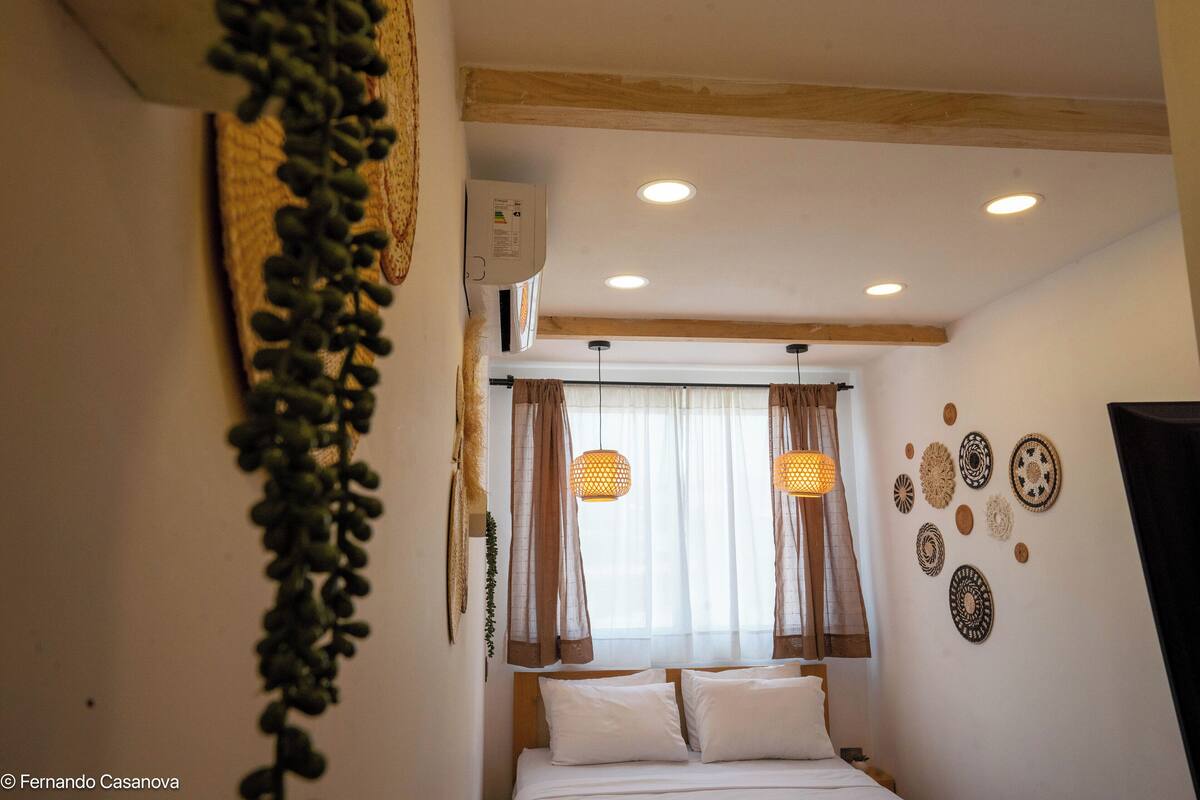 A bedroom with a bed, curtains, wall decorations, and an air conditioning unit.