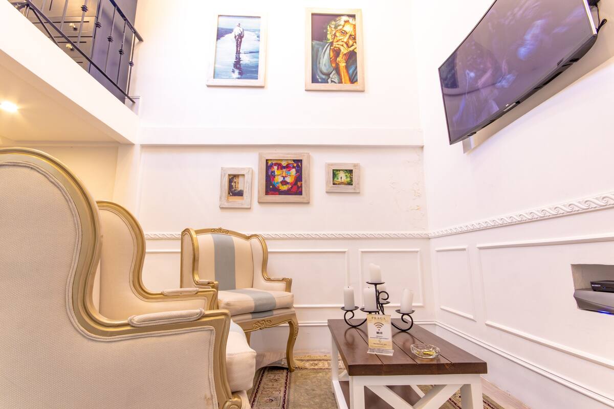 A room with a sofa, a table with candles, and framed artwork on the wall.