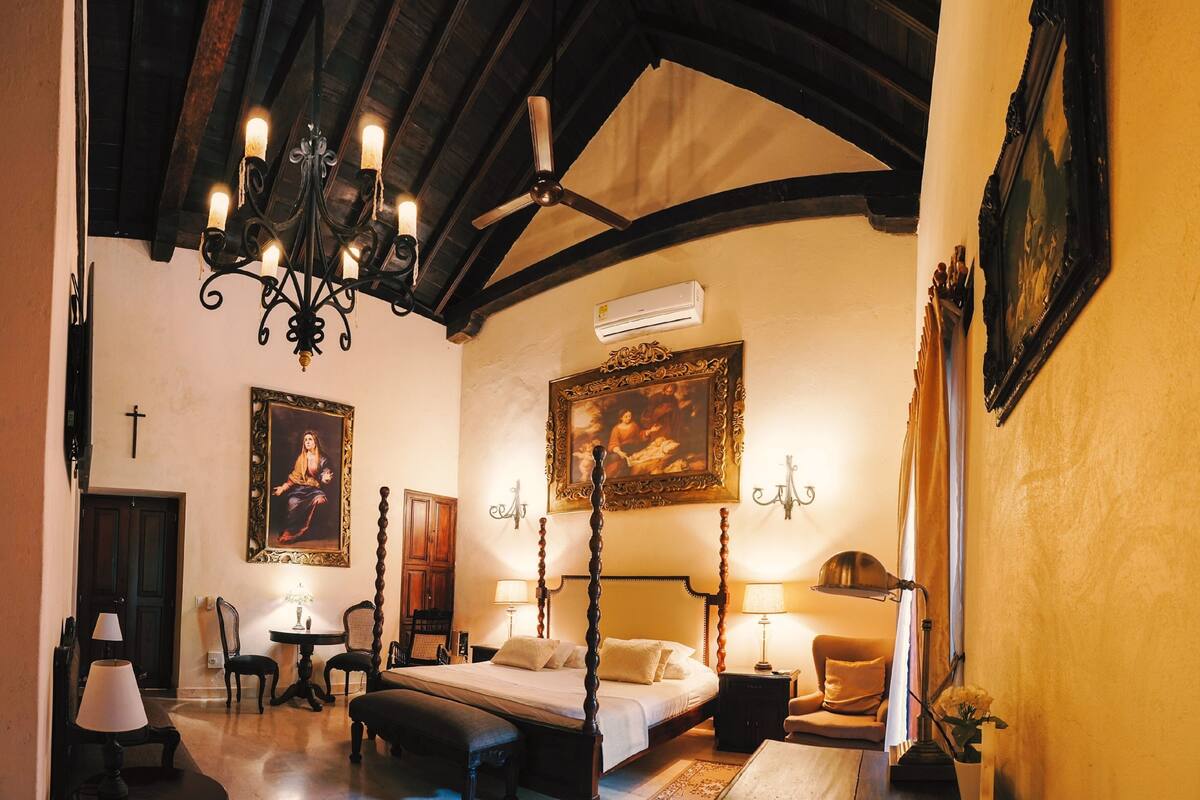 Une chambre à coucher de style traditionnel, avec un lit à baldaquin, un lustre et un grand tableau accroché au mur.