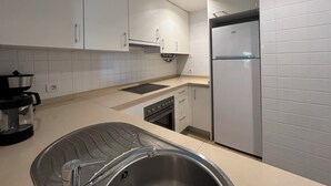 Uma cozinha moderna com armários brancos, forno embutido, lava-louças e geladeira.