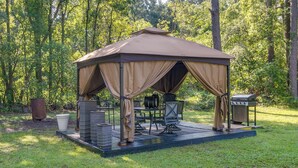A gazebo with a table and chairs, surrounded by a grassy area and trees. - Waycross Vacation Rental w/ Private Backyard! (Waycross)
