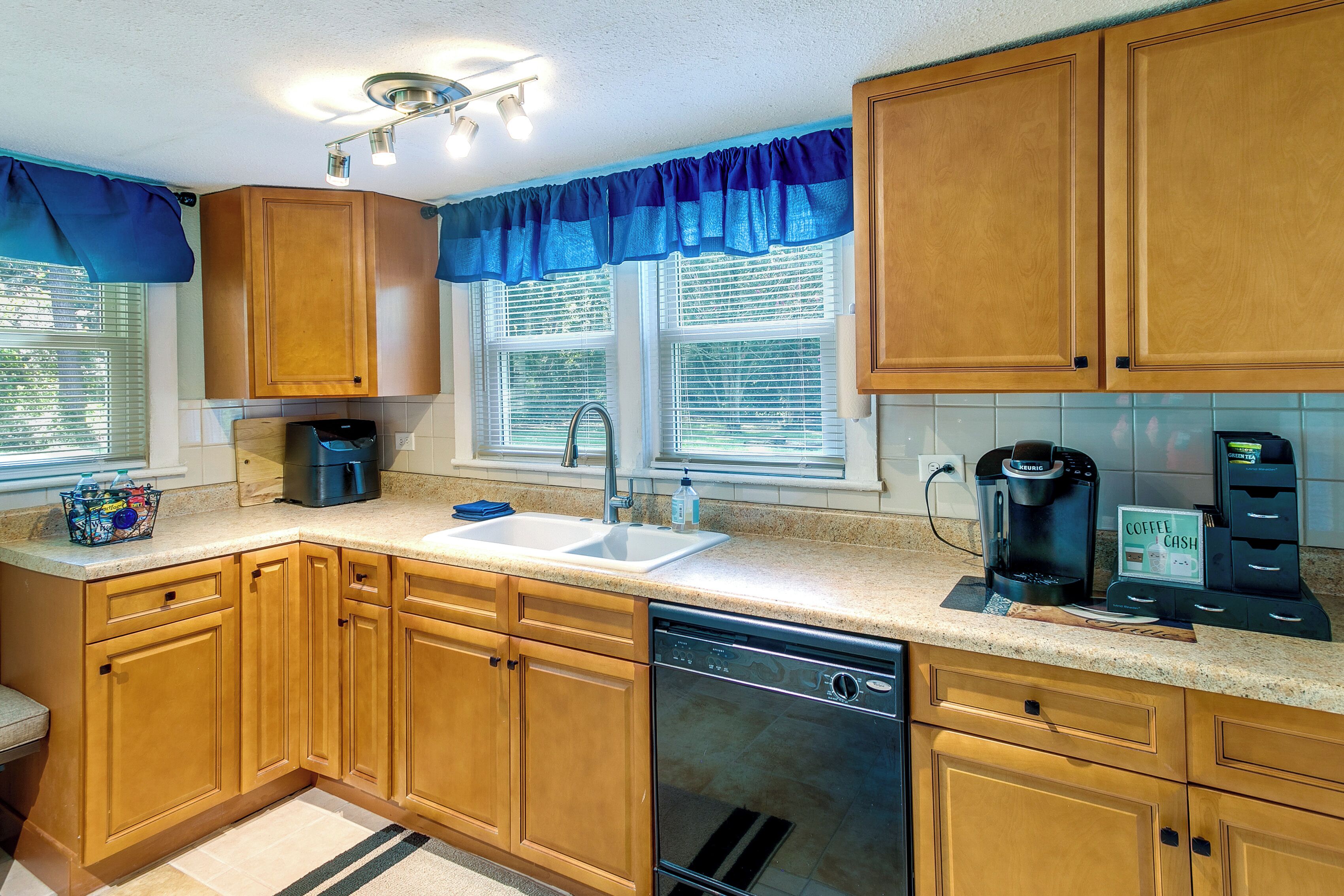 A kitchen with wooden cabinets, a dishwasher, a coffee maker, and a coffee cash machine.
