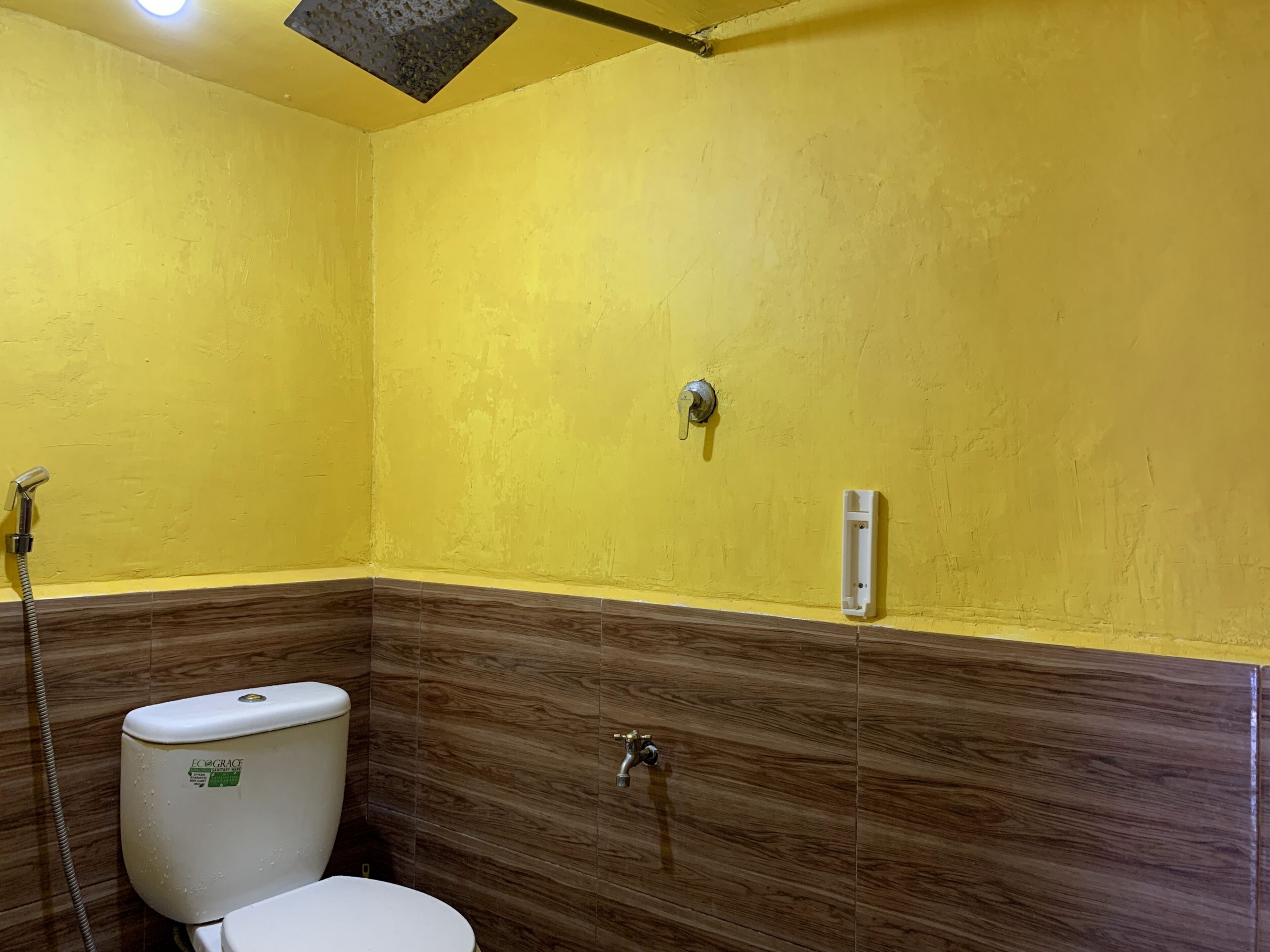 A bathroom with a yellow wall, a toilet, a shower, and a towel rack.