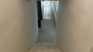 Un escalier étroit aux marches carrelées menant à l’étage supérieur, bordé de murs sobres.