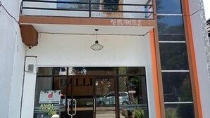 Un bâtiment doté d’une entrée en verre, d’un balcon et d’une enseigne sur laquelle on peut lire « DALLI ».