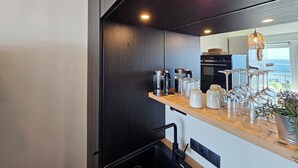 A modern kitchen with a wooden countertop, built-in appliances, and a view of the ocean. - One-room apartment Kaiserhof 311 Norderney with sea view directly on the beach (Norderney)