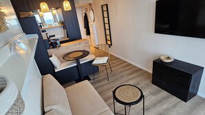 A modern living room with a large sofa, a coffee table, and a flat-screen TV mounted on the wall. - One-room apartment Kaiserhof 311 Norderney with sea view directly on the beach (Norderney)