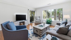 Een woonkamer met een televisie, bank, fauteuil en salontafel.