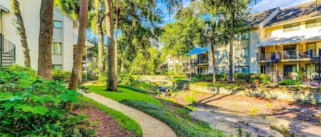 A residential area with a pathway, trees, and buildings with balconies.