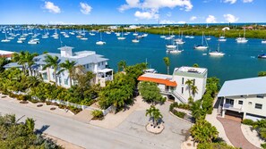 A marina with multiple boats, surrounded by residential buildings with balconies and palm trees.
