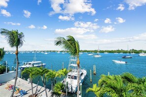 A marina with boats docked, palm trees, and a clear blue sky.
