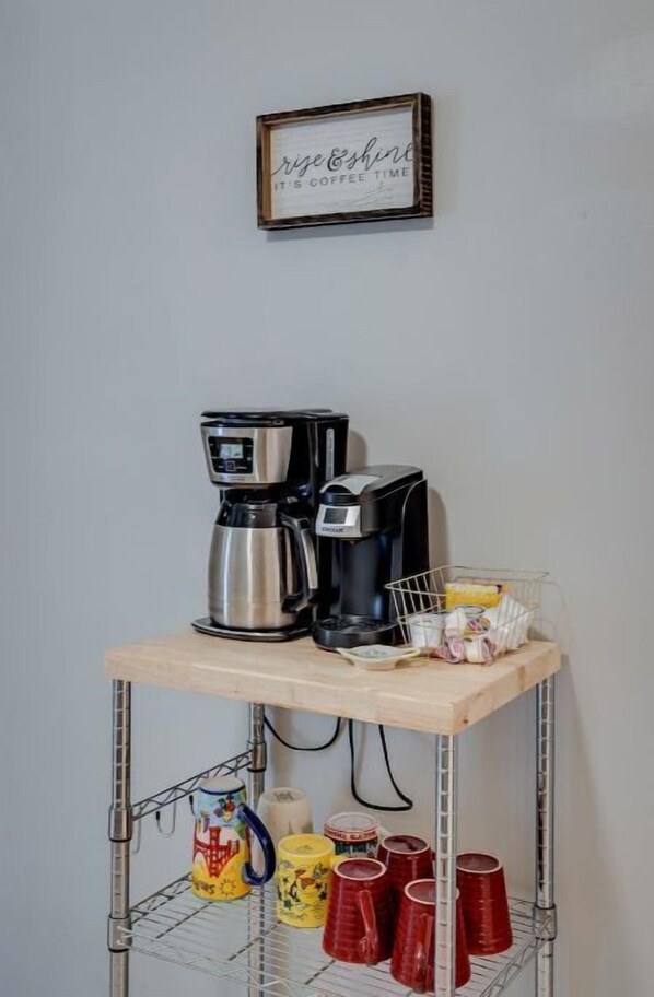A coffee station with two coffee makers and a shelf with mugs and a basket. - Close to ULM & Meta, Pet Friendly, Fiber Internet, Carport! (Monroe)