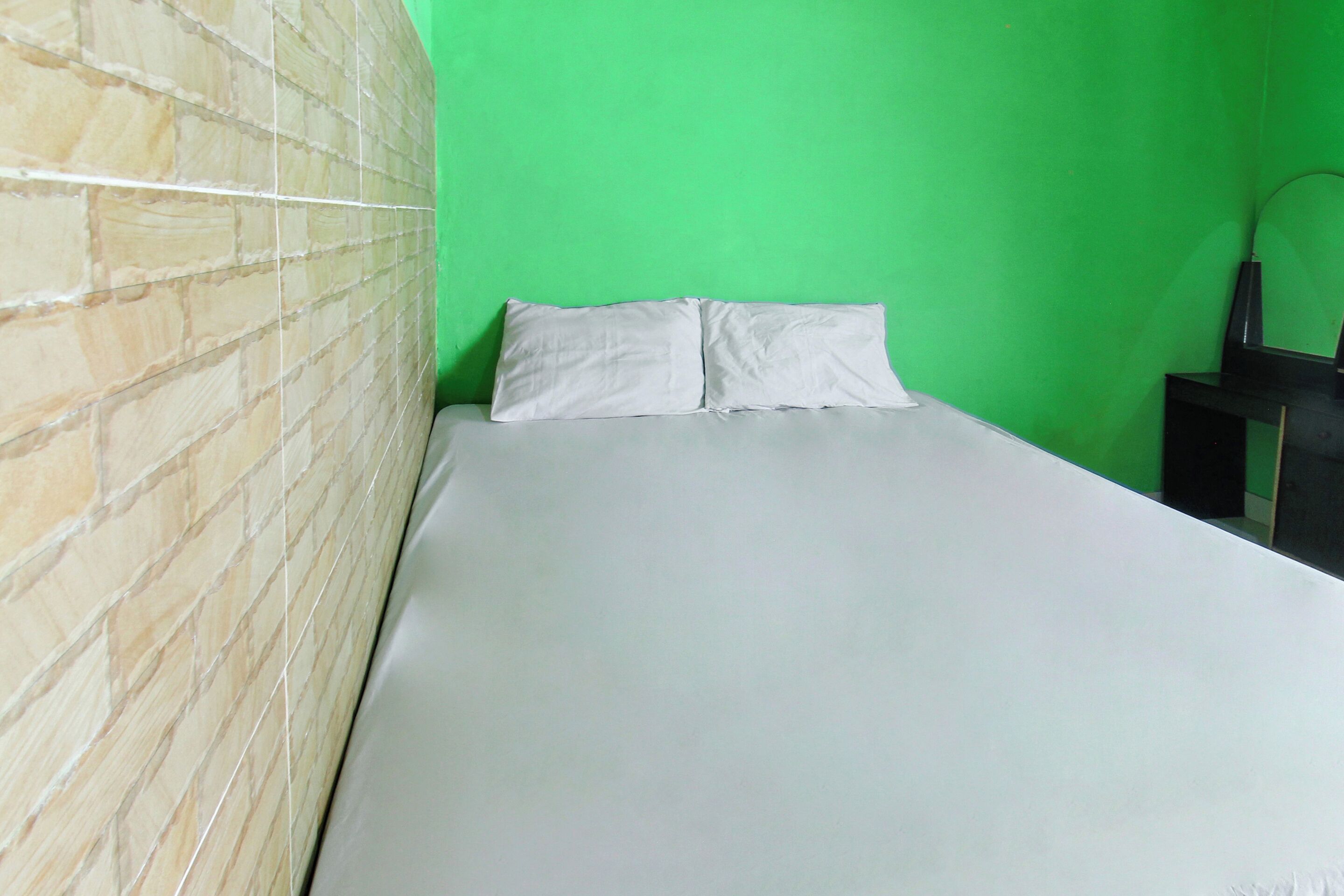 A room with a brick-patterned wall, a bed with white bedding, and a green wall.