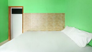A room with a bed, a brick-patterned headboard, and a green wall. - Hotel O Jayanni (Sumbawa Besar)