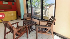 A reception area with a wooden reception desk, multiple wooden chairs, and a tiled floor. - Hotel O Jayanni (Sumbawa Besar)