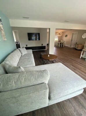 Relax in this stylish living room with a large sofa, flat-screen TV, and dining area.
