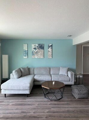 Relax in this stylish living room with a light grey sofa, round coffee table, and patterned ottoman.