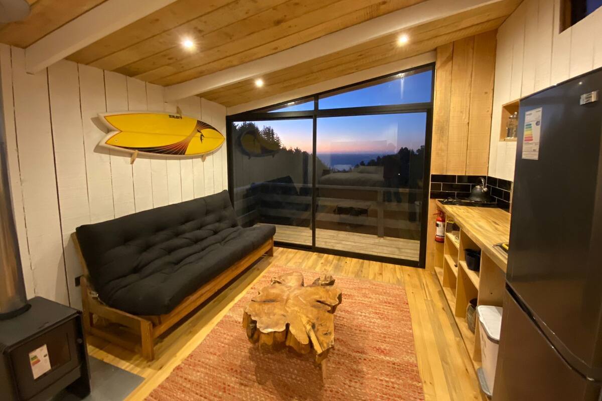 Una cocina moderna con un ventanal grande, un sofá negro y una mesa de centro de madera.