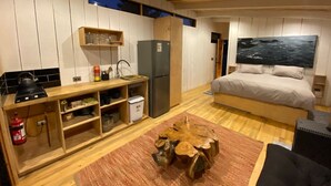 A compact bedroom with a bed, a small kitchenette, and a large window. - Cabañas La Ola Puertecillo (Navidad)