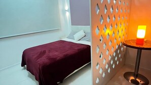 A bedroom with a bed, a nightstand, and a wall-mounted light fixture. - Stúdio Praia Ipanema (Rio de Janeiro)