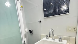 A bathroom with a white sink, a black toilet, and a glass shower enclosure. - Stúdio Praia Ipanema (Rio de Janeiro)