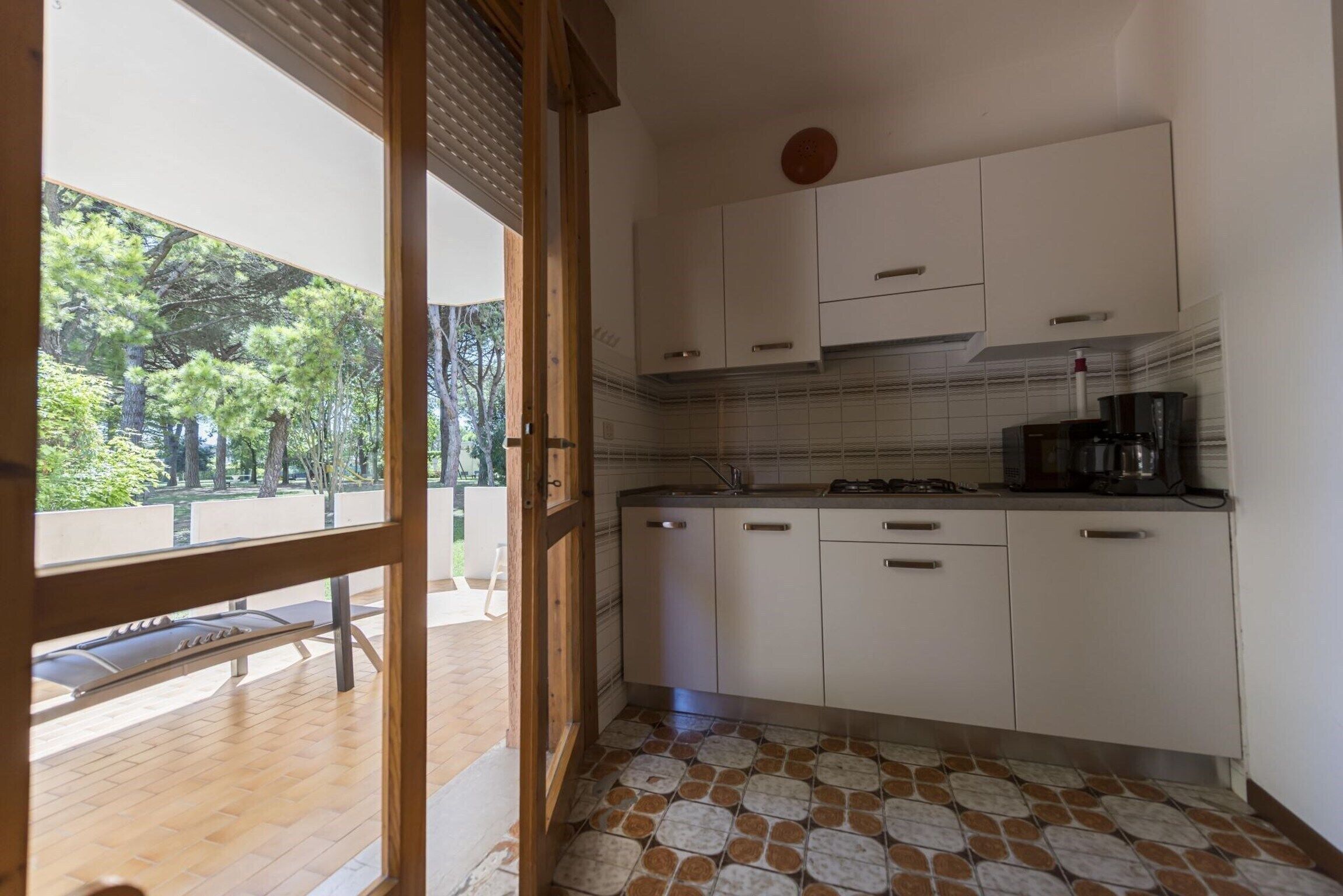 A kitchen with white cabinets, a tiled backsplash, and a coffee maker on the counter.