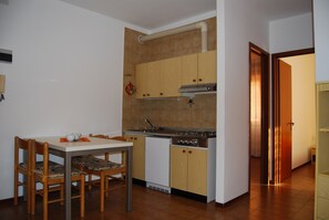 A compact kitchen with a dining table and chairs, a built-in oven, and a sink. - Homely Flat few Minutes From the Beach - Beahost (San Michele al Tagliamento)