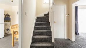 Un escalier dont les marches sont recouvertes de moquette, menant à une porte blanche.