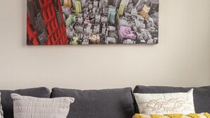 Un canapé gris avec trois coussins : un blanc, un avec un motif jaune et un autre avec un motif blanc et jaune.
