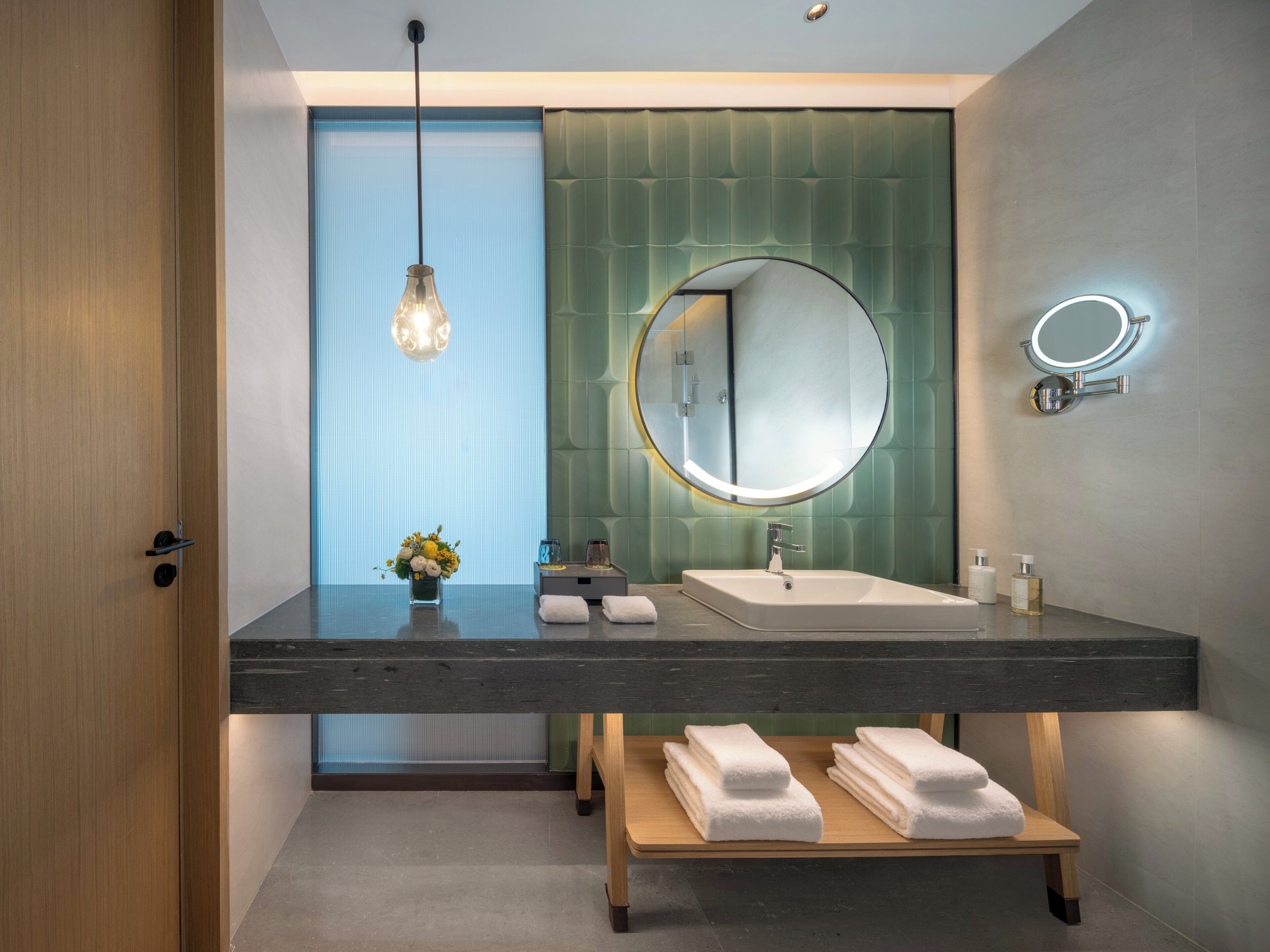 Un bagno moderno con uno specchio grande, due lavabi, un mobile bagno in legno e un lampadario.