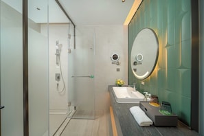 A modern bathroom with a glass-enclosed shower, a sink with a mirror, and a towel on the counter.