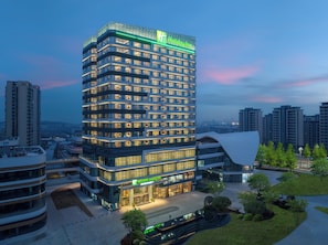 A multi-story Holiday Inn hotel with a modern design, featuring a prominent glass facade and a rooftop terrace. - Holiday Inn Chengdu East by IHG (Chengdu)