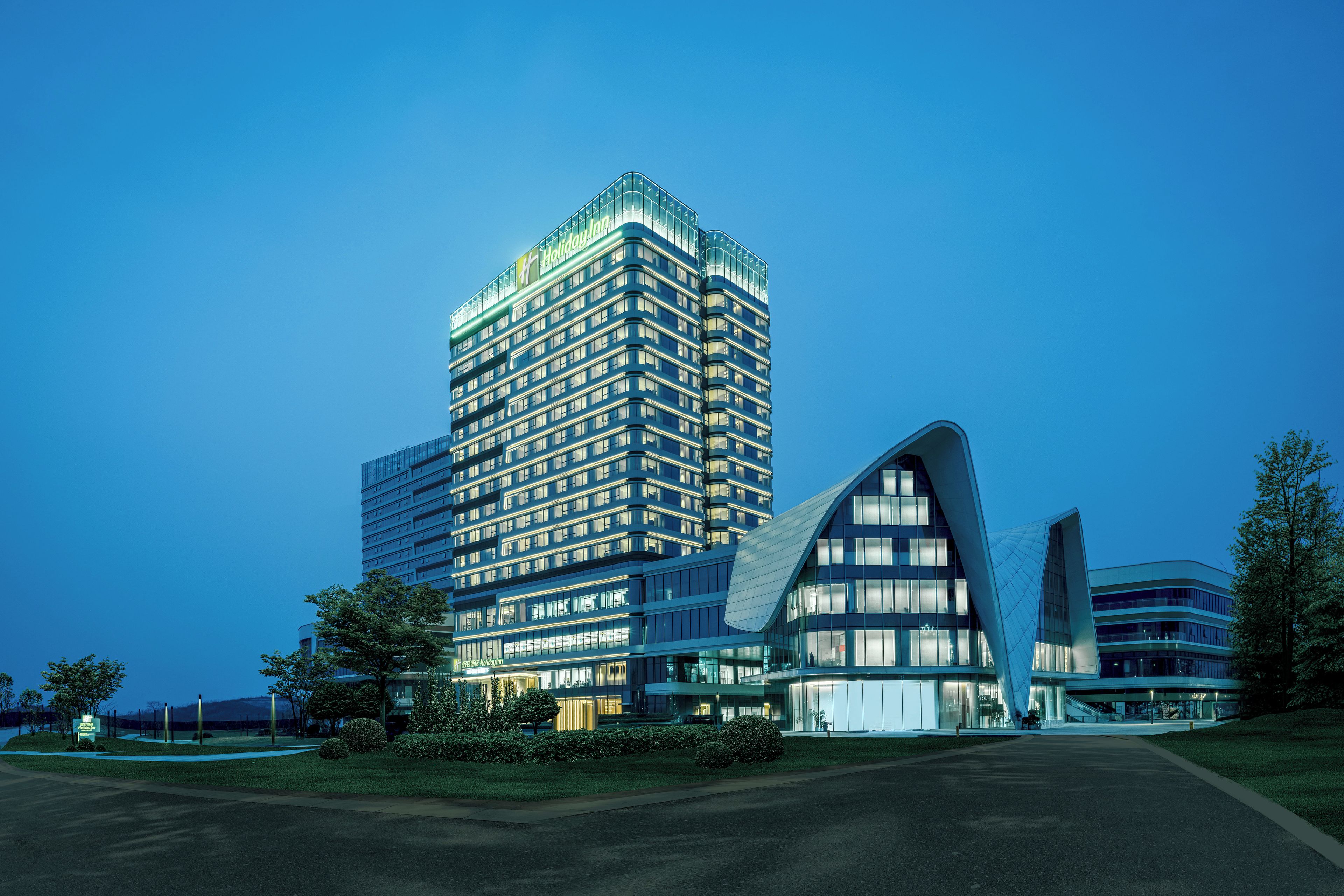 Un hotel moderno con un edificio prominente en esquina y una estructura curva.