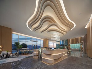 A modern hotel lobby with a curved ceiling, a reception desk, and a view of the cityscape. - Holiday Inn Chengdu East by IHG (Chengdu)