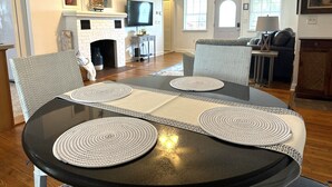 A dining area with a round table, four chairs, and a fireplace. - 1 Minute Walk to Ocean-Charming Downtown Beachside Home with Mother-In-Law Suite (Cocoa Beach)