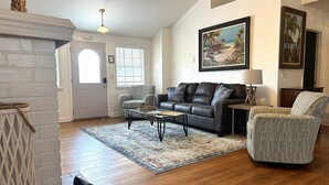 A living room with a fireplace, a sofa, a coffee table, and a patterned rug. - 1 Minute Walk to Ocean-Charming Downtown Beachside Home with Mother-In-Law Suite (Cocoa Beach)